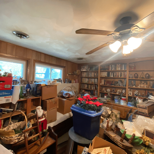 A cluttered living room in Binghamton, New York, before Decluttering Chaos organizing services, filled with boxes and household items awaiting sorting and decluttering to restore functional living space