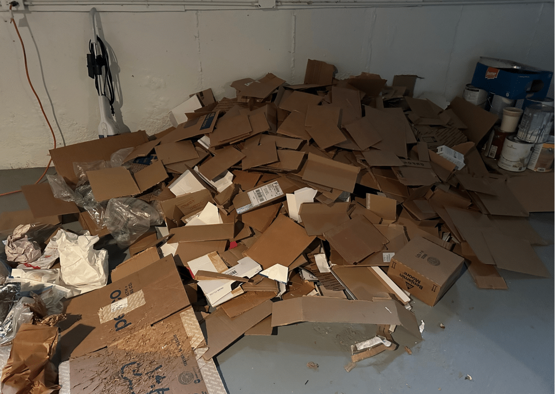 Pile of flattened cardboard boxes in a Binghamton, New York basement during a Decluttering Chaos organizing project, showing progress in recycling and clearing clutter