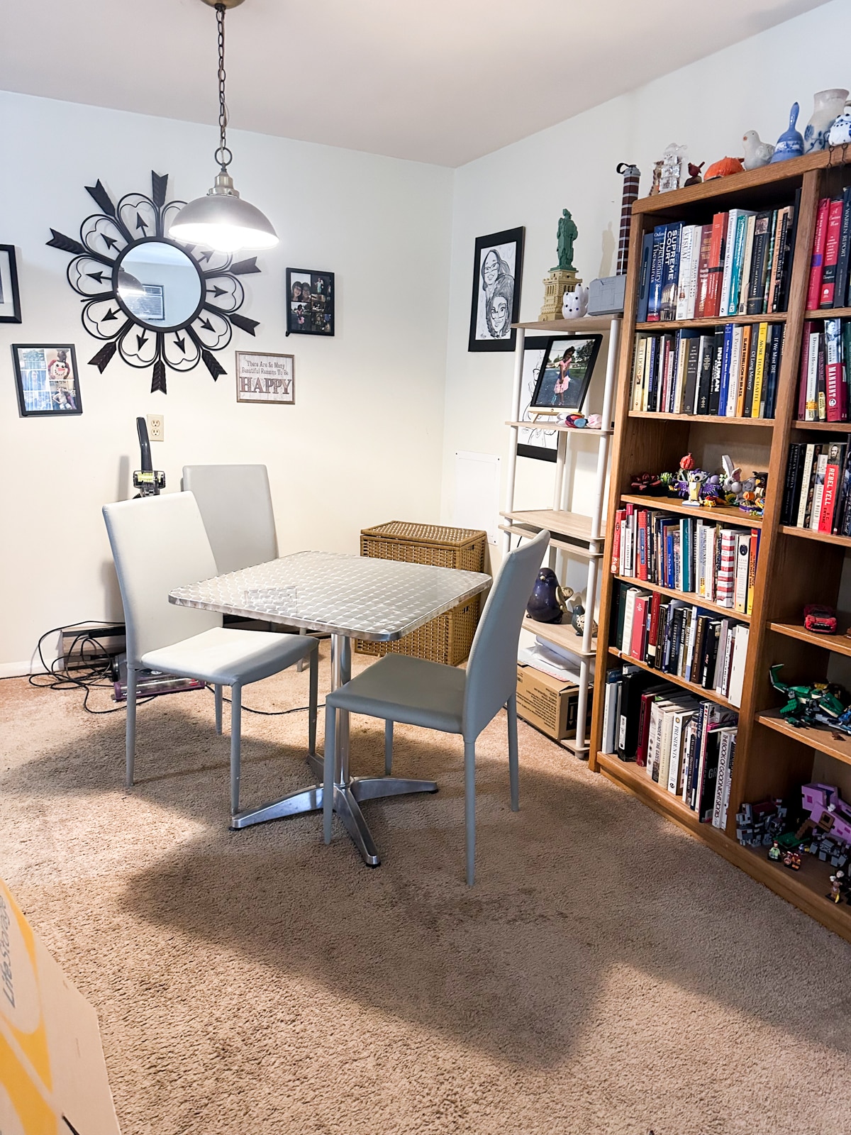 A tidy and inviting dining area in Vestal, New York, after Decluttering Chaos organizing services, featuring a small table with modern chairs, a bookshelf, and a wall mirror creating a cozy, functional space