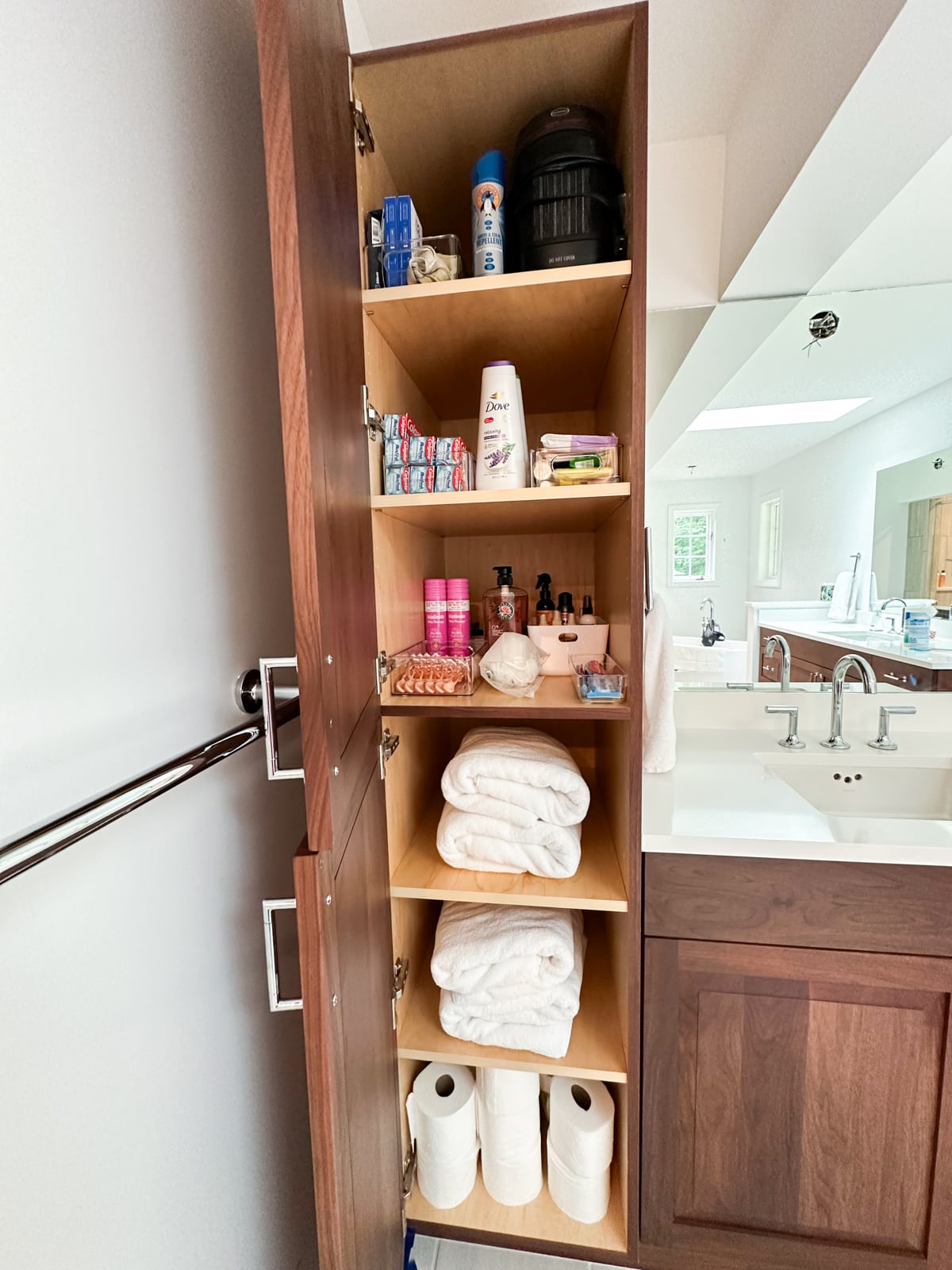 A neatly organized bathroom cabinet in Vestal, New York, arranged by Decluttering Chaos with towels, toiletries, and household supplies each placed in designated spaces for intentional and functional storage