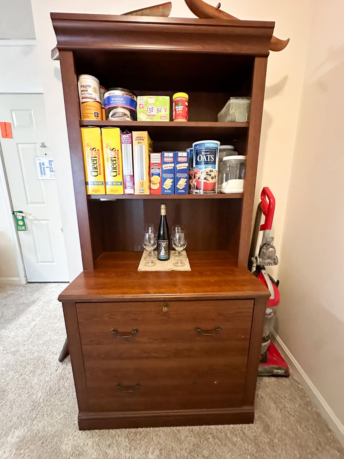 A repurposed wooden cabinet in a Vestal, New York home, organized by Decluttering Chaos to store pantry items and household essentials as part of a creative, budget-friendly organizing solution