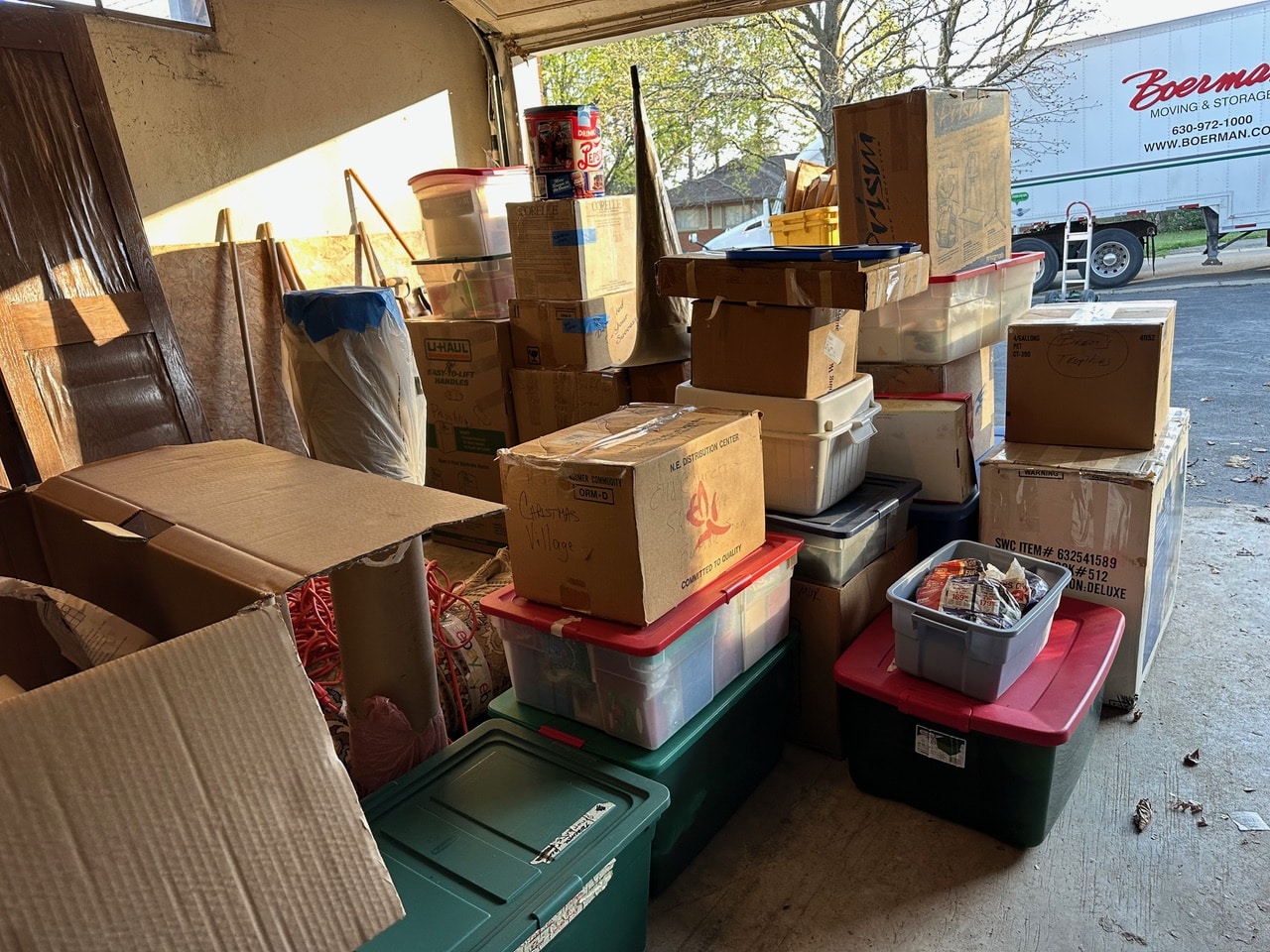  Stacks of boxes and storage bins neatly arranged in a garage during a Decluttering Chaos project in Ithaca, New York, showing the decluttering and sorting stage before a move or downsizing